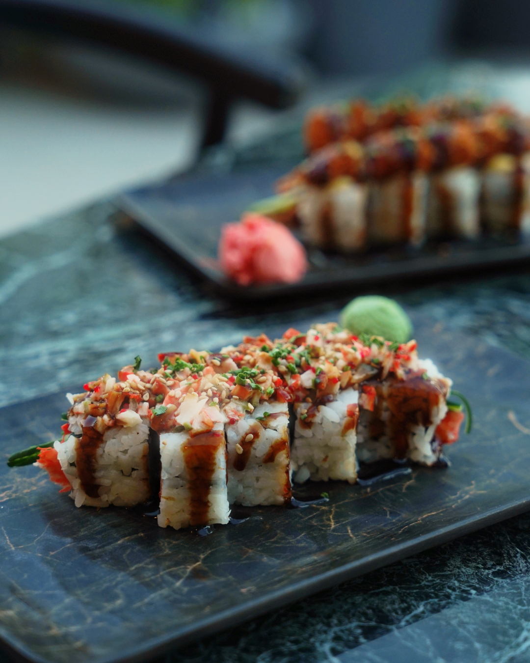 Close-up of a topped sushi roll on a slate plate