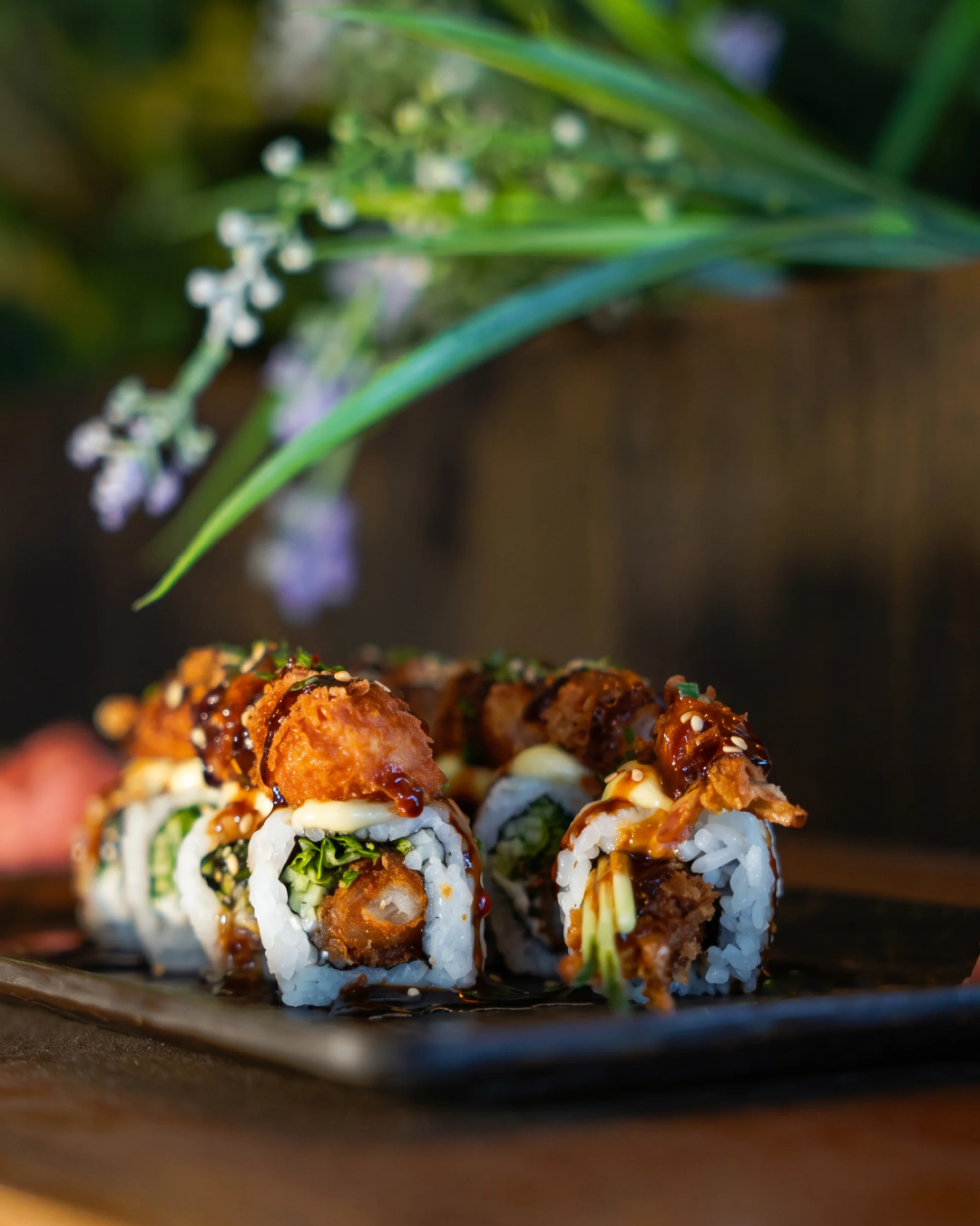Crispy sushi roll plated among greenery
